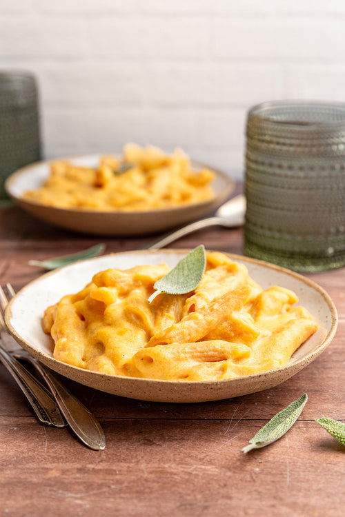Pasta dish with a leaf on top in a bowl on a wooden table