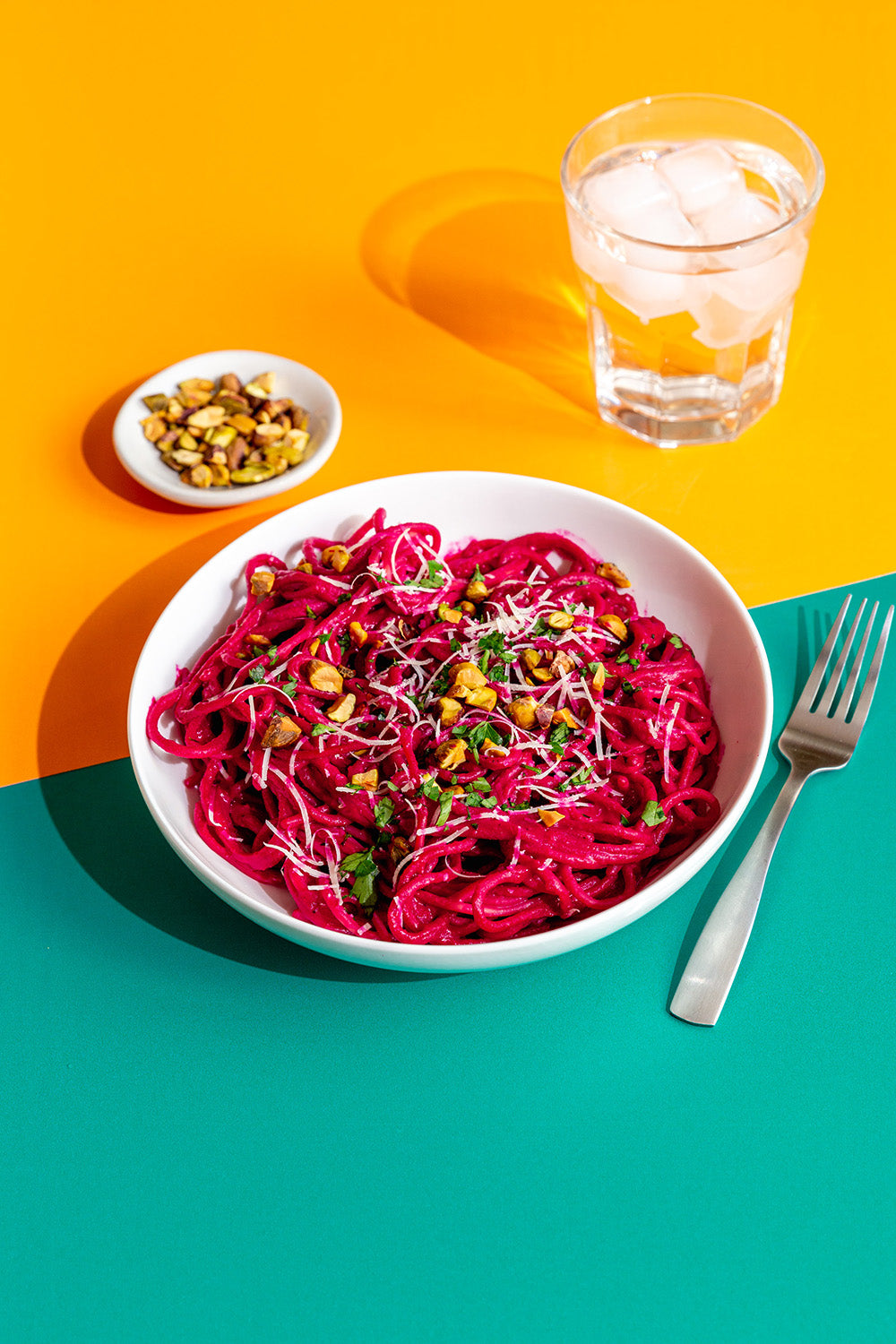 Bowl of pink pasta with chickpeas on a yellow and blue background