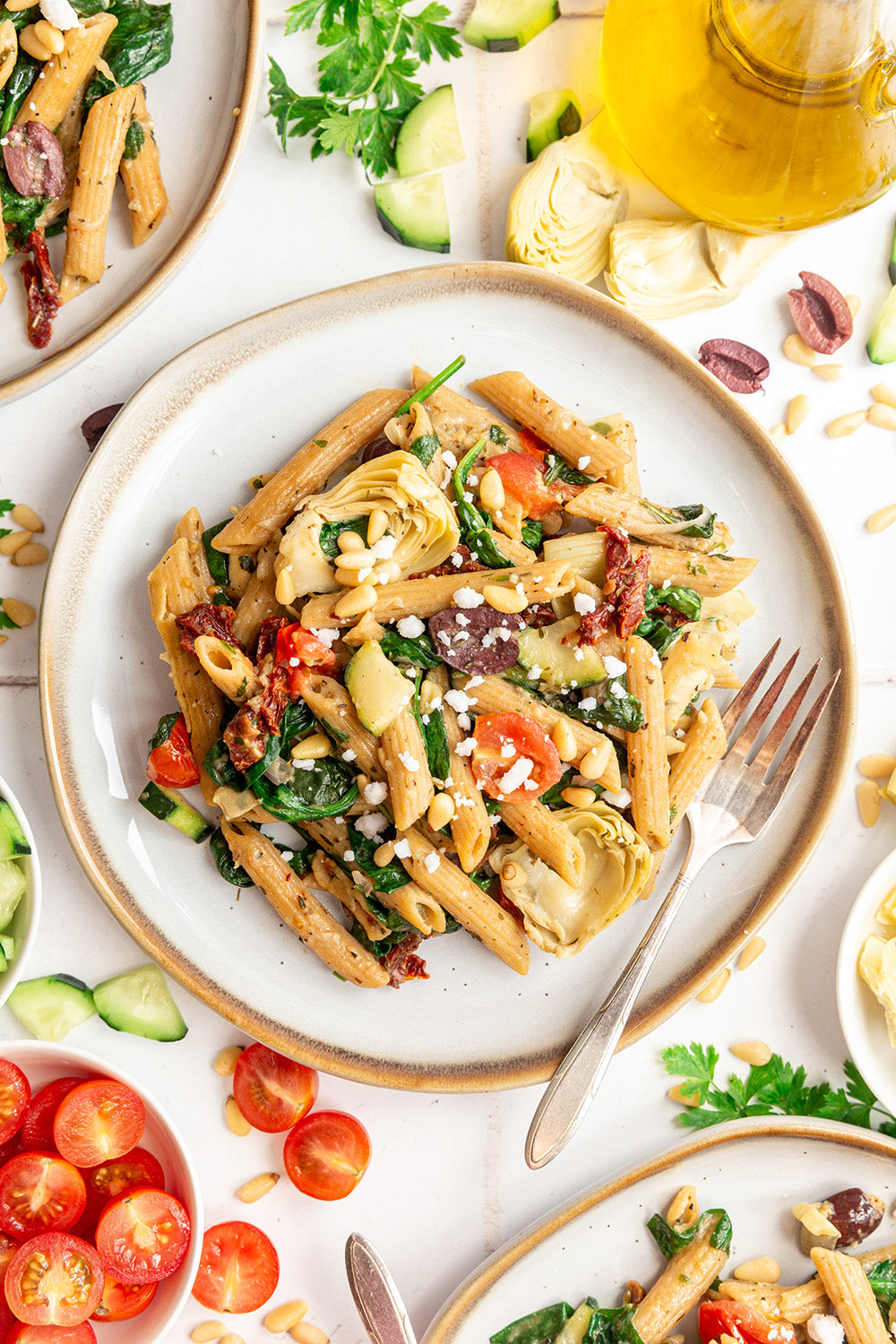 Pasta dish with vegetables on a white plate with a fork, surrounded by ingredients.