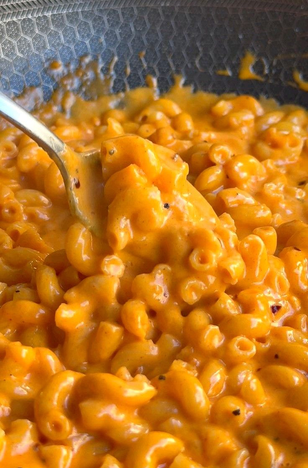 Macaroni and cheese being scooped with a spoon from a pot.